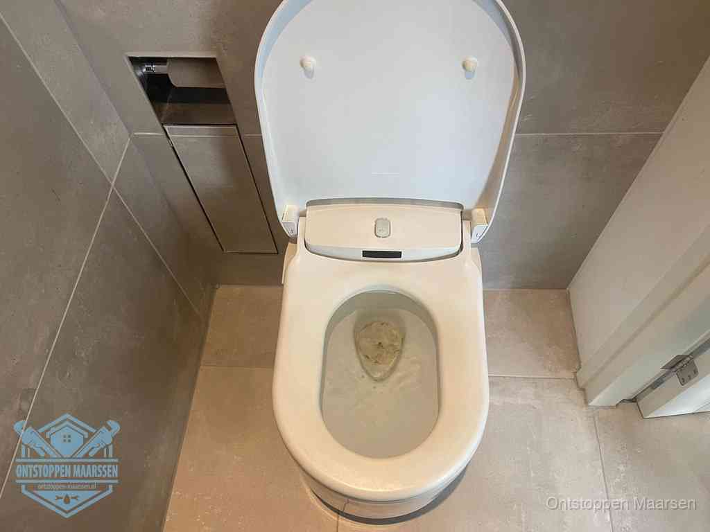 Een wit hangtoilet waarin een prop wc-papier op het water blijft drijven, een duidelijk signaal van een verstopte wc in Maarssen