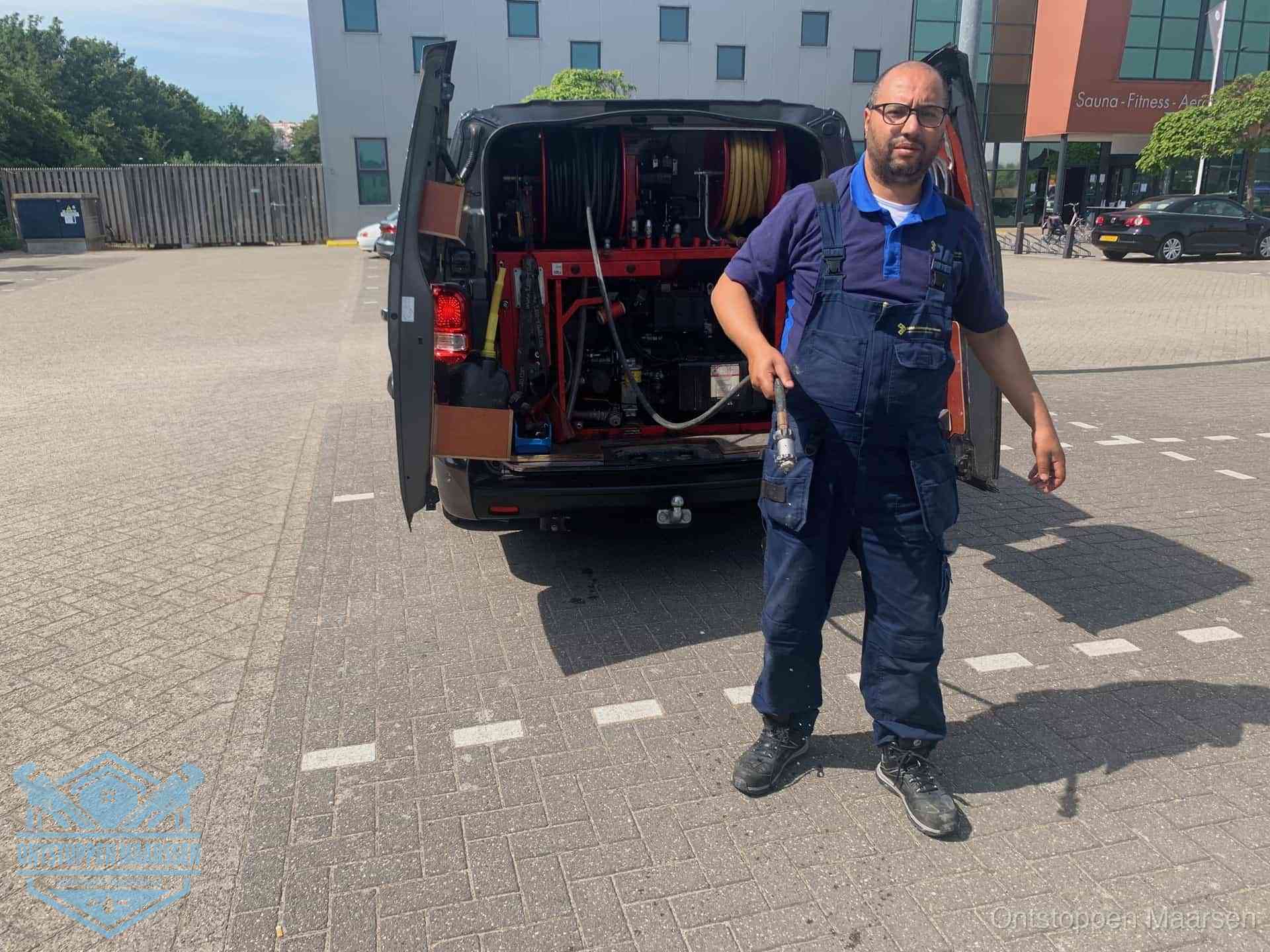Een monteur bij zijn bestelbus met een hogedruk- en rioolreinigingsunit, klaar om de oorzaak van terugkerende wc-verstoppingen aan te pakken in Maarssen
