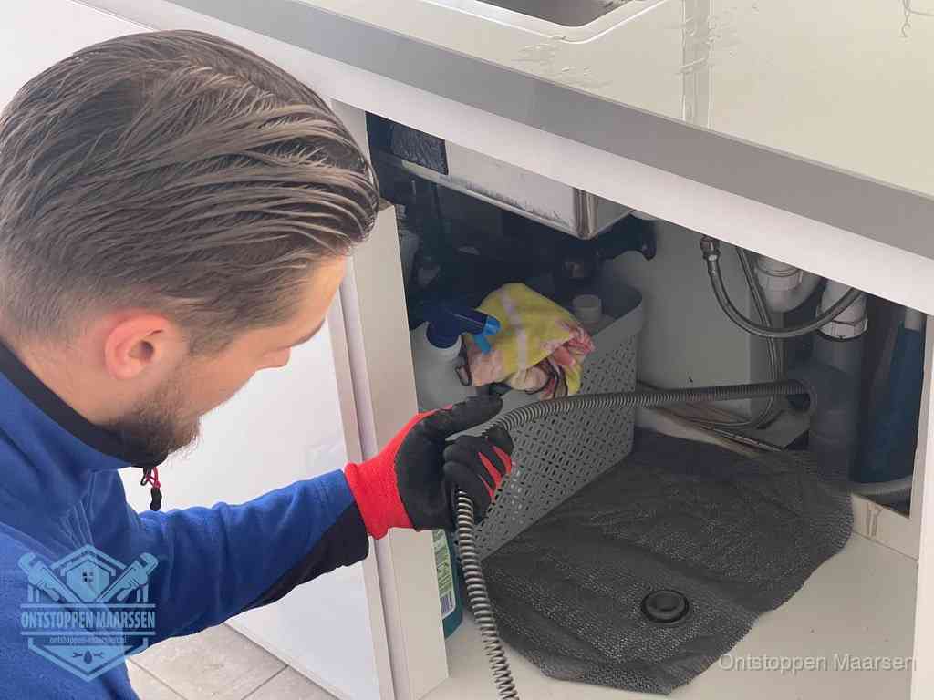 Een monteur voert een flexibele ontstoppingsveer in de afvoer om een verstopping voorbij de bocht van het toilet te bereiken in Maarssen