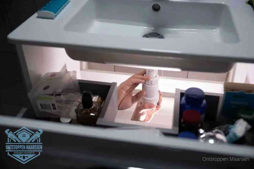 Een pompfles met zeep boven een wastafel in de toiletruimte, de warm water en afwasmiddel-methode om de wc te ontstoppen in Maarssen