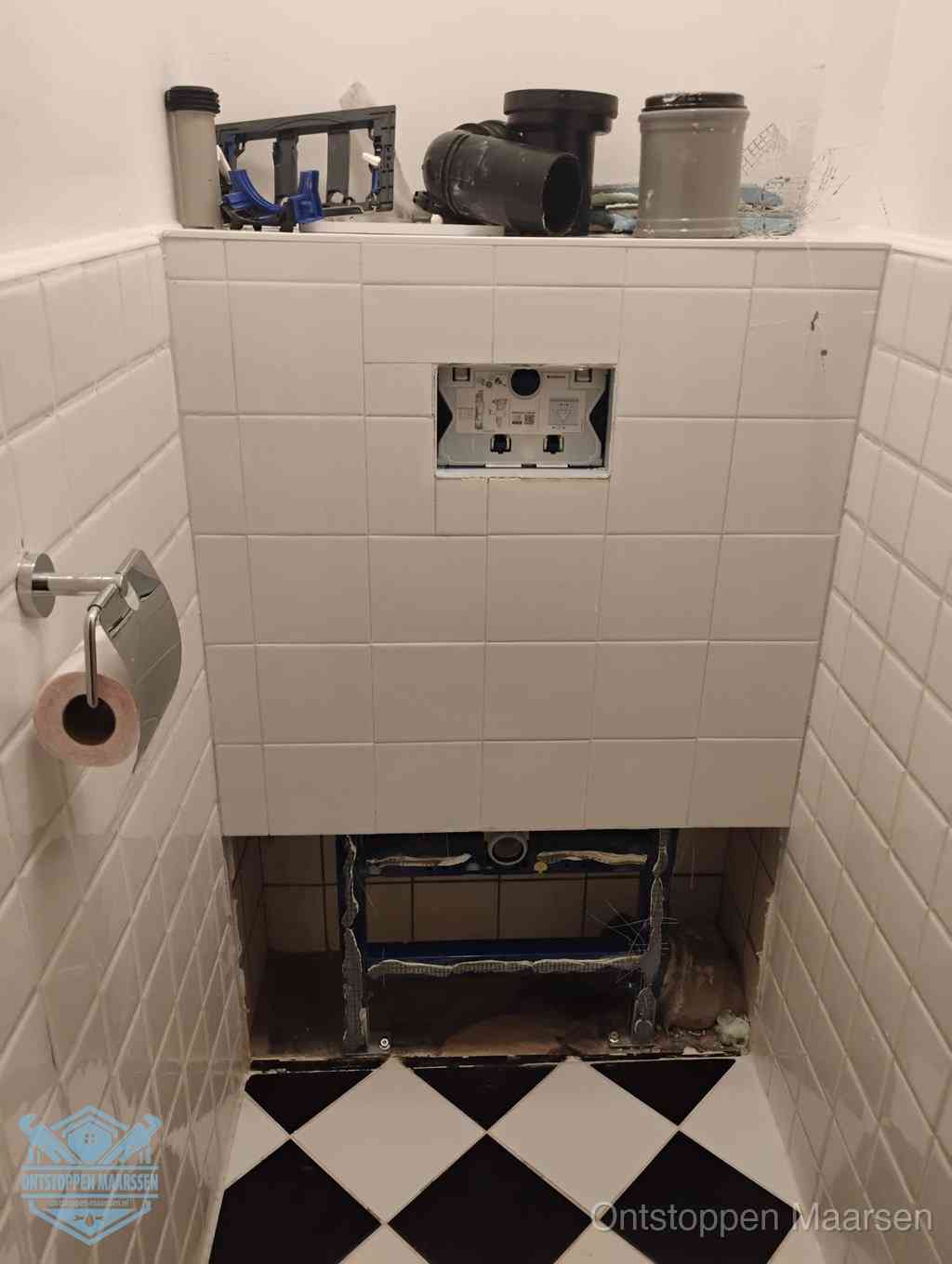 Een toiletruimte waar het hangtoilet en de inbouwreservoir-onderdelen zijn vrijgelegd voor onderhoud, periodiek nazicht voorkomt een wc-verstopping in Maarssen